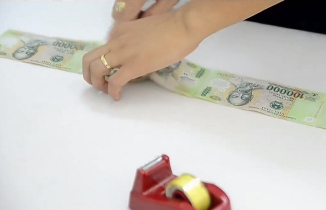 Dùng băng dính để dán nối tiếp các tờ tiền với nhau