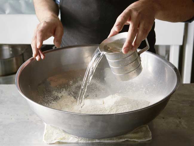Cho nước 35 độ C vào bột làm bánh